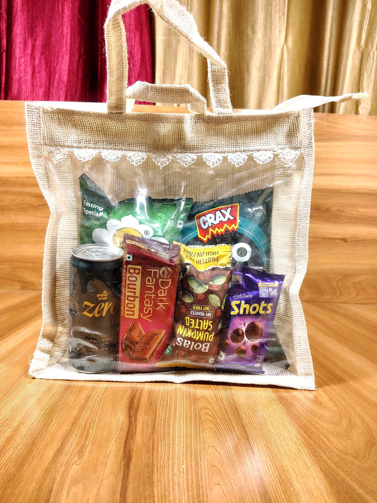 Festive jute gift bag with a clear window showing snacks and chocolates